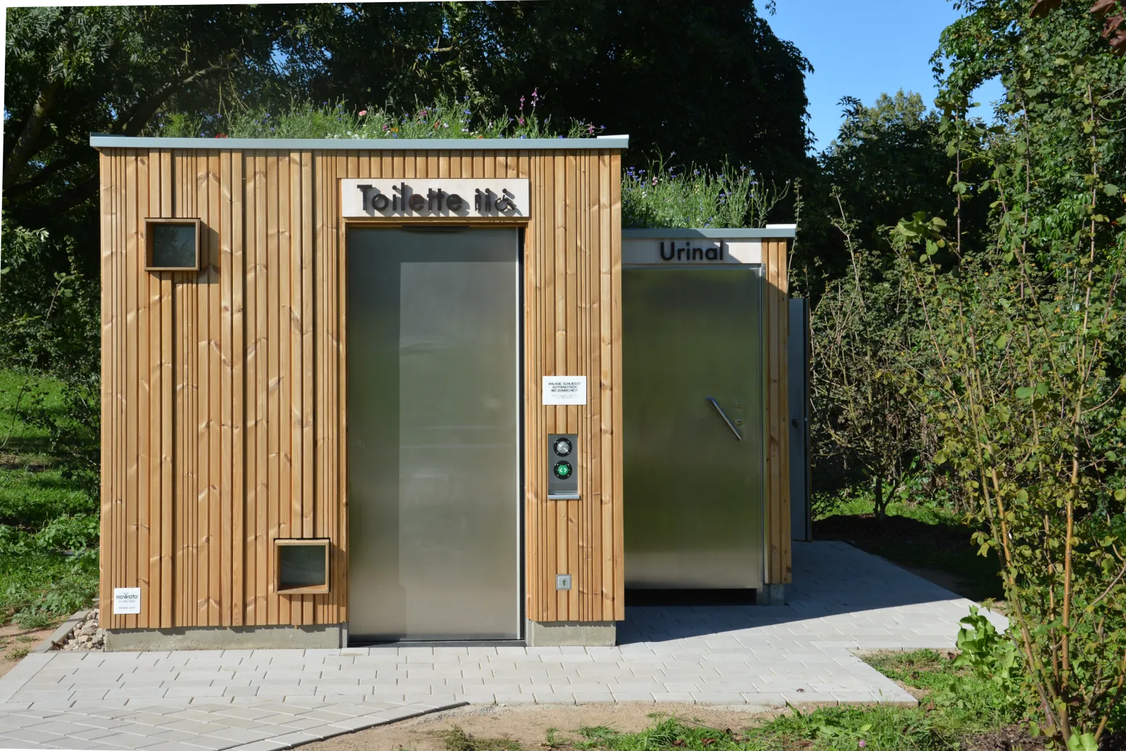 Barrierefreie öffentliche Toilettenanlage KUBUS nach DIN 18040 mit separatem wasserlosem Pissoir, Trockentrenntoilettensystem ECODOMEO, robustem Lärchenholz-Design und autarker Nutzung ohne Wasseranschluss – nachhaltig und hygienisch für Parkplätze, Rastplätze und öffentliche Bereiche