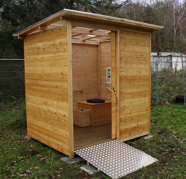 Komposttoilette 'Wald barrierefrei' mit 80L-Behälter. Hundeschule Eigenart. Aussenansicht mit Einblick in das Toilettenhäuschen.