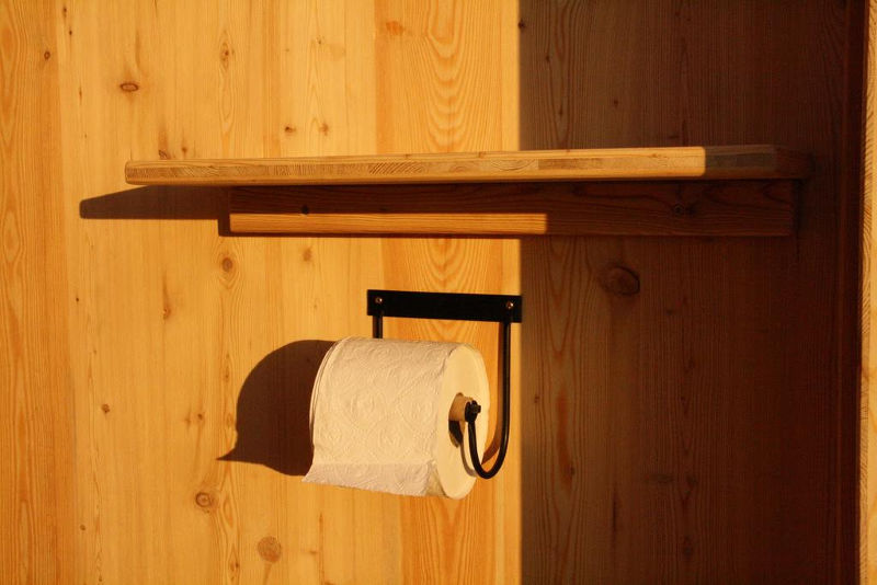 Toilettenhaeuschen Wald. Standard Ausstattung Toilettenpapierhalter und Ablagebrett