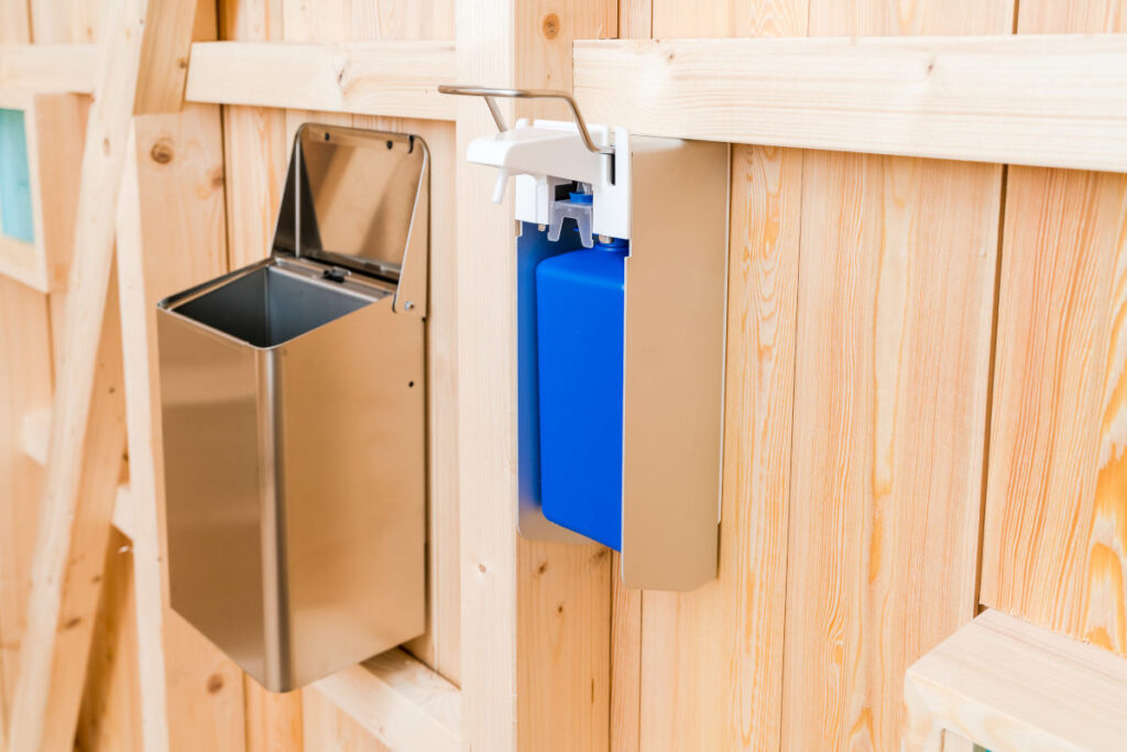 Trockentoilette KUBUS - öffentliche Toilette aus Lärchenholz mit Toilettensystem ECODOMEO - Wandmülleimer aus Edelstahl und Handgelspender