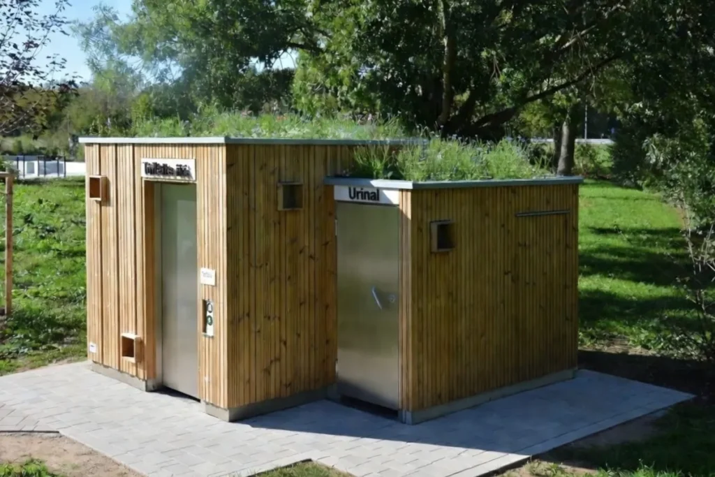 Barrierefreie, autarke Toilettenanlage KUBUS aus Holz mit Gründach im Park: Trockentoilette (Toilette ohne Wasser) nach DIN-Norm zugänglich und separates Urinal (Pissoir)